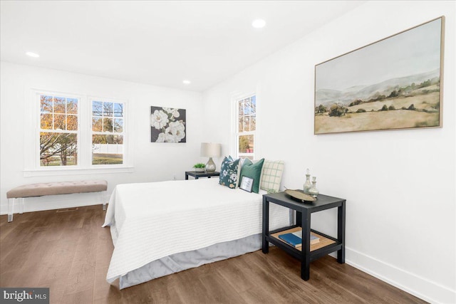 bedroom with dark hardwood / wood-style floors and multiple windows