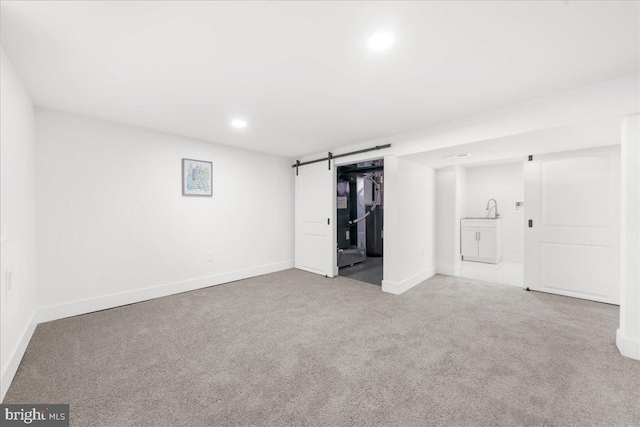 basement featuring a barn door and light colored carpet