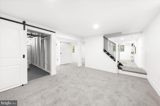 basement featuring a barn door and light colored carpet