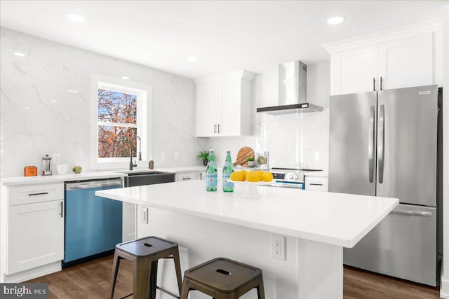 kitchen with white cabinetry, dark wood-type flooring, stainless steel appliances, and wall chimney range hood