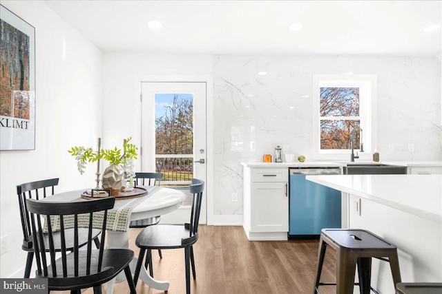 kitchen featuring white cabinetry, sink, stainless steel dishwasher, and light hardwood / wood-style floors