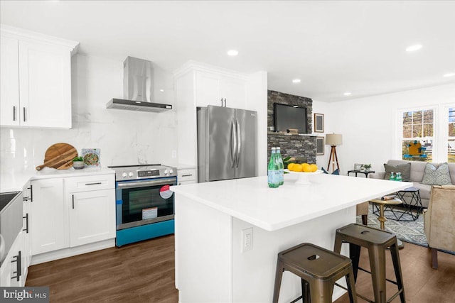 kitchen featuring white cabinetry, wall chimney exhaust hood, stainless steel appliances, dark hardwood / wood-style floors, and a breakfast bar