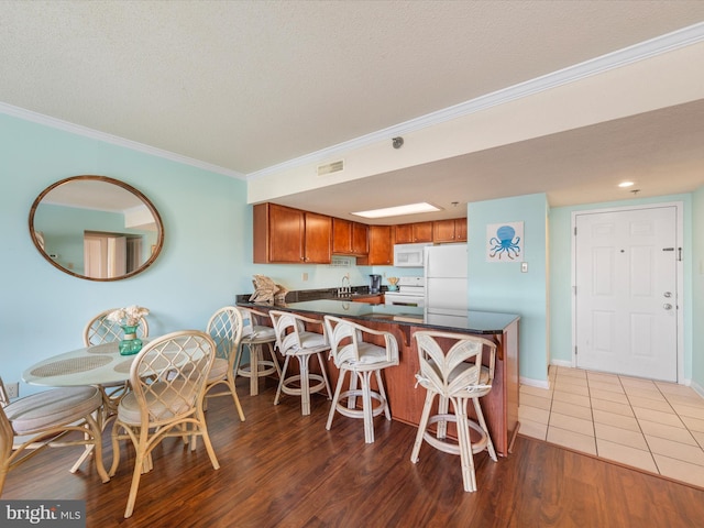 kitchen with sink, dark hardwood / wood-style flooring, white appliances, and kitchen peninsula