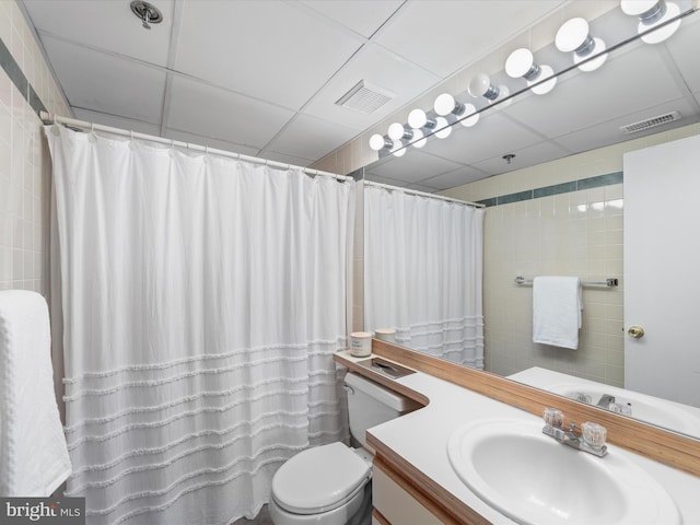 bathroom featuring a paneled ceiling, curtained shower, vanity, and toilet