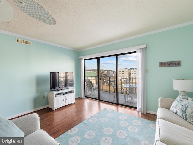 living room featuring hardwood / wood-style floors, ceiling fan, crown molding, and a textured ceiling