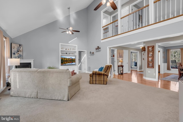 living room with ceiling fan, light hardwood / wood-style floors, and high vaulted ceiling