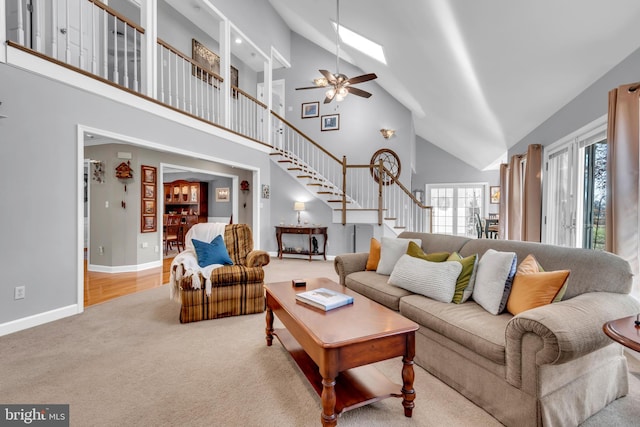 living room featuring a skylight, ceiling fan, light hardwood / wood-style flooring, and high vaulted ceiling