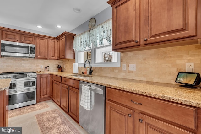 kitchen featuring light stone countertops, backsplash, stainless steel appliances, sink, and light tile patterned floors