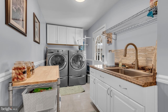 clothes washing area with washer and dryer, cabinets, light tile patterned floors, and sink