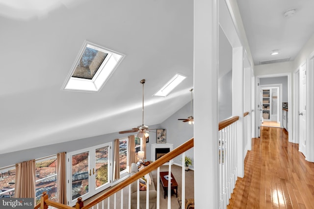 hallway featuring lofted ceiling with skylight and light hardwood / wood-style flooring