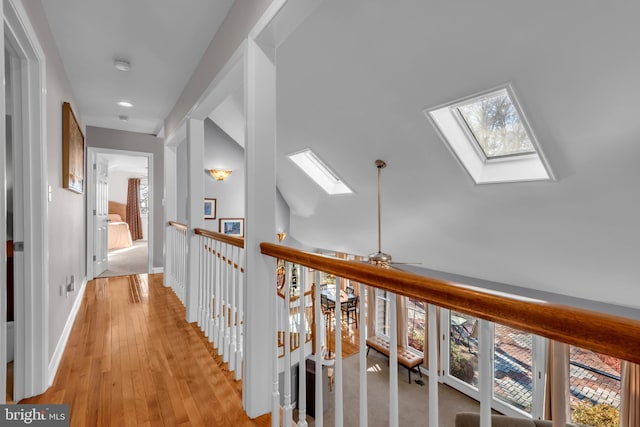 corridor featuring plenty of natural light, light wood-type flooring, and a skylight