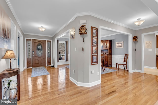 foyer entrance with light hardwood / wood-style floors and crown molding