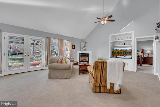 living room with ceiling fan, french doors, built in features, high vaulted ceiling, and light colored carpet