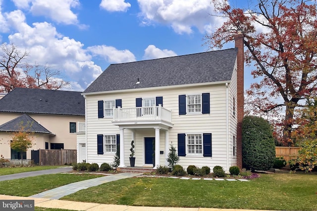 colonial-style house with a balcony and a front lawn