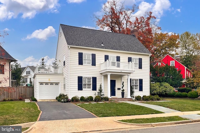 view of front of property featuring a balcony, a front yard, and a garage