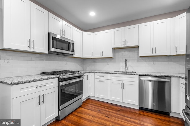 kitchen featuring backsplash, sink, dark hardwood / wood-style floors, appliances with stainless steel finishes, and white cabinetry