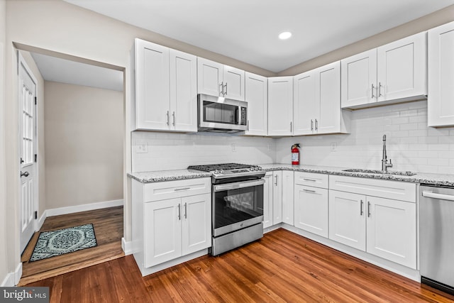 kitchen with hardwood / wood-style floors, stainless steel appliances, white cabinetry, and sink