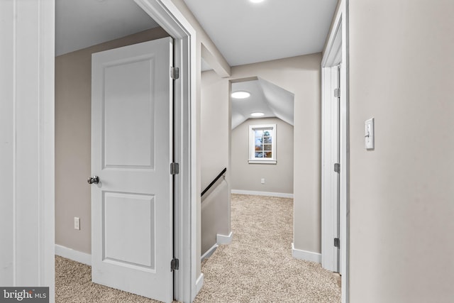 corridor featuring light carpet and vaulted ceiling