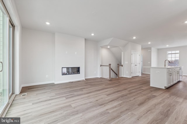 unfurnished living room with light hardwood / wood-style flooring and sink