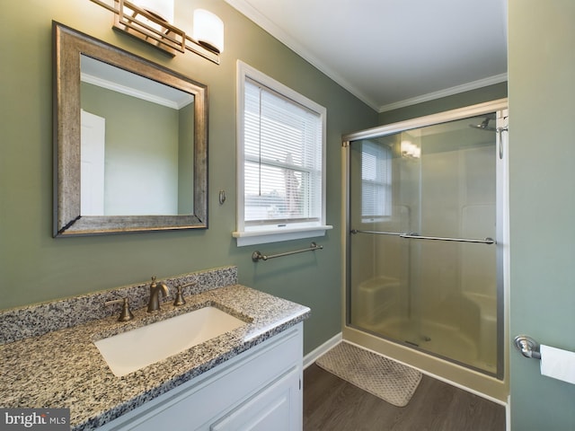 bathroom featuring vanity, hardwood / wood-style flooring, a shower with door, and ornamental molding