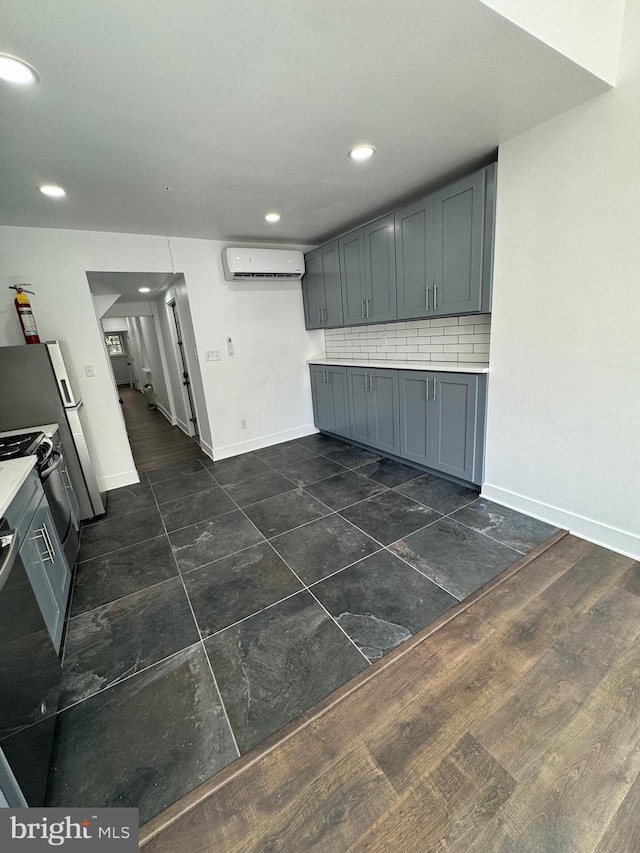 kitchen with dark wood-type flooring, tasteful backsplash, an AC wall unit, range with electric stovetop, and gray cabinets