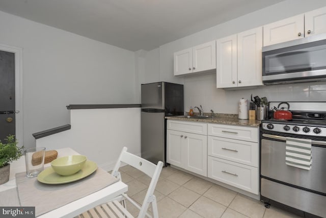 kitchen with decorative backsplash, dark stone countertops, white cabinetry, and appliances with stainless steel finishes