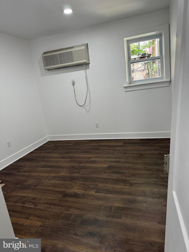 spare room featuring an AC wall unit and dark wood-type flooring