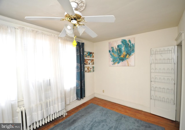 empty room featuring ceiling fan, dark hardwood / wood-style flooring, and radiator heating unit