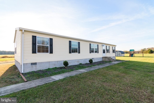 view of front of house featuring a playground, a front yard, and a storage unit