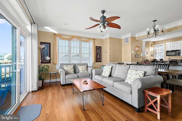 living room with ceiling fan with notable chandelier, light hardwood / wood-style flooring, and ornamental molding