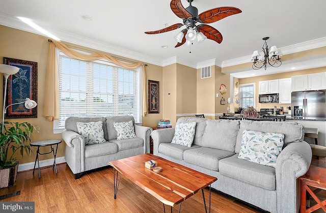 living room with ornamental molding, a healthy amount of sunlight, ceiling fan with notable chandelier, and light wood-type flooring