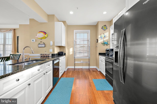 kitchen with a healthy amount of sunlight, sink, black appliances, and light hardwood / wood-style floors