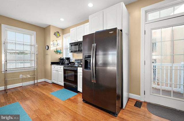 kitchen featuring white cabinetry, light hardwood / wood-style flooring, and black appliances