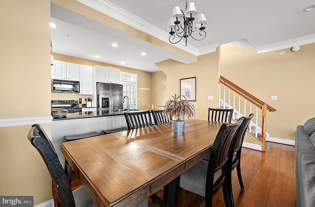 dining room with a chandelier, light hardwood / wood-style floors, ornamental molding, and sink