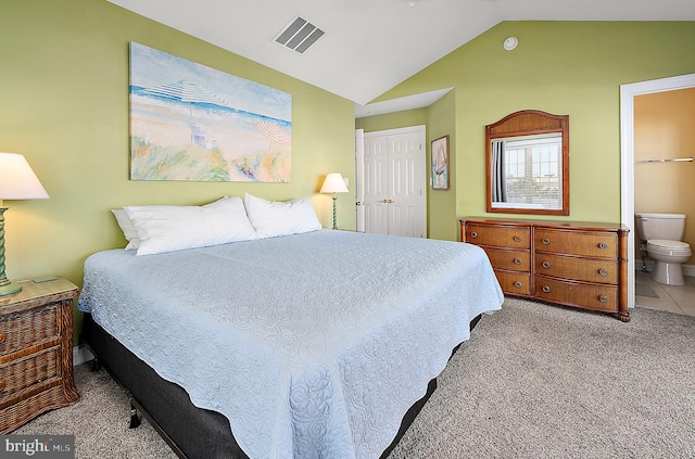 carpeted bedroom with connected bathroom, a closet, and vaulted ceiling