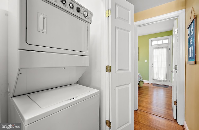 washroom with stacked washing maching and dryer and light hardwood / wood-style floors