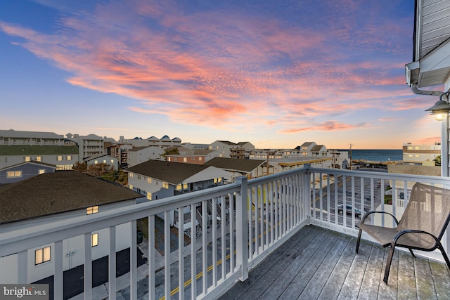 deck at dusk featuring a water view