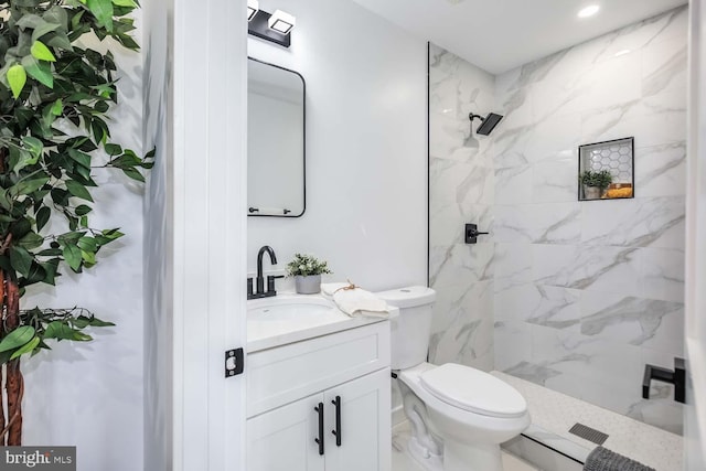 bathroom with vanity, toilet, and tiled shower