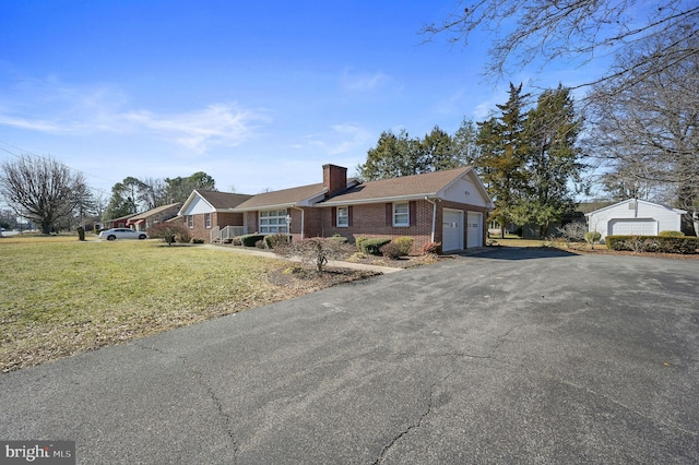 single story home featuring aphalt driveway, an attached garage, brick siding, a front lawn, and a chimney