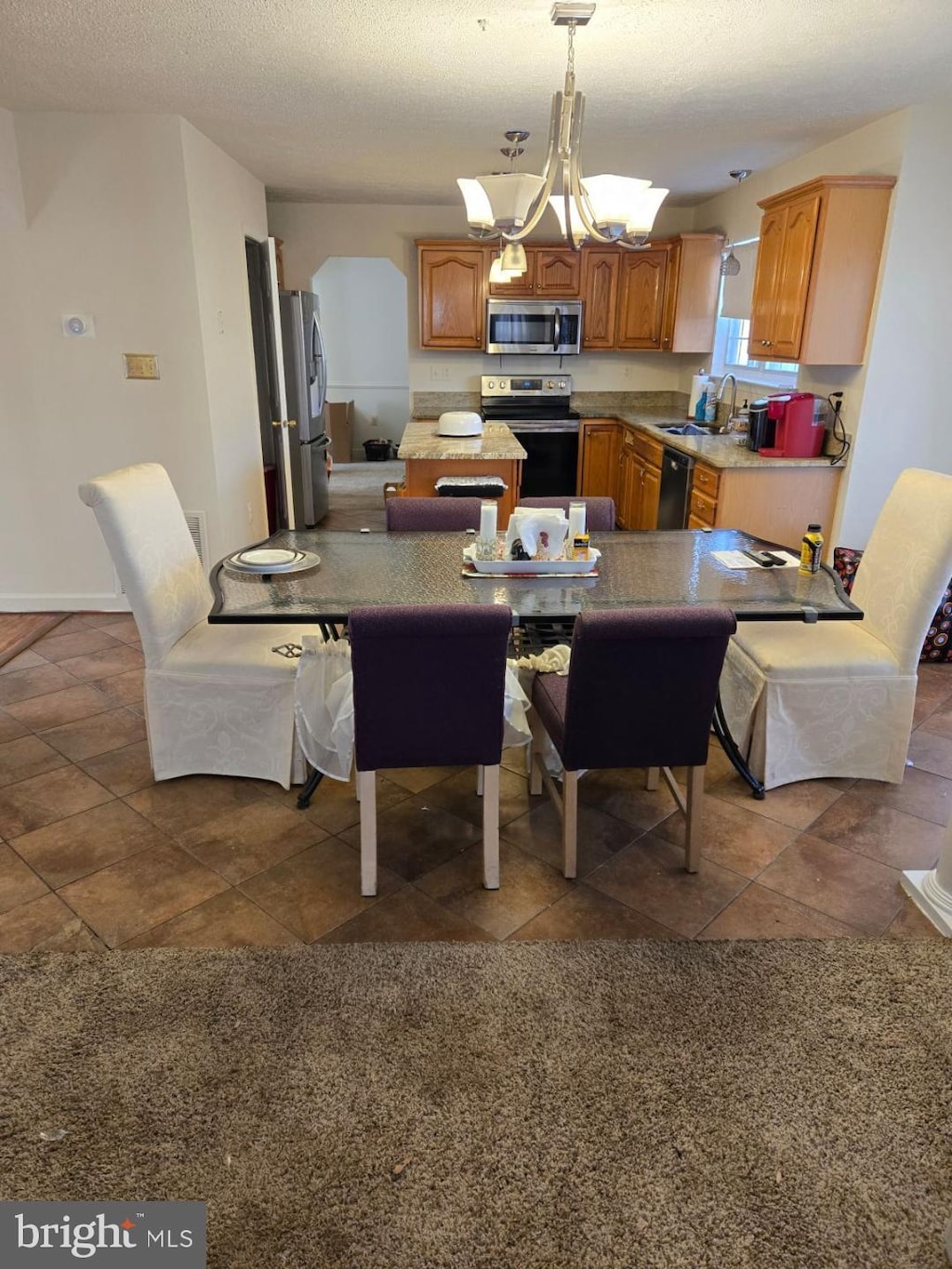 dining room with an inviting chandelier, sink, and a textured ceiling