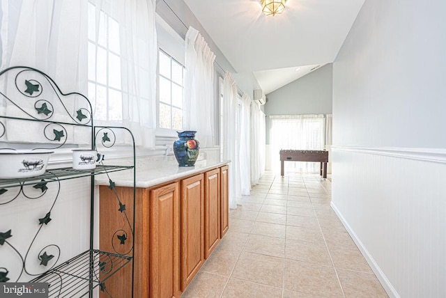 hall with light tile patterned flooring and vaulted ceiling