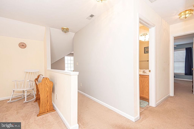 hall with light carpet, sink, and vaulted ceiling