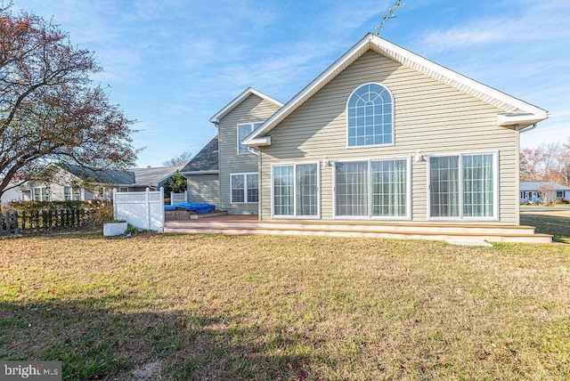 back of property with a lawn and a deck