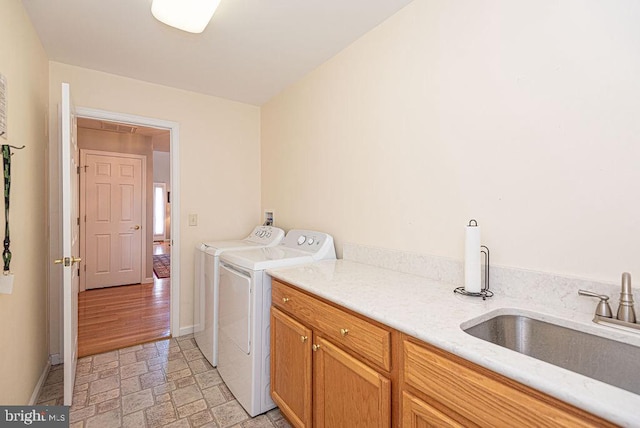 washroom featuring washer and dryer, cabinets, sink, and light hardwood / wood-style flooring