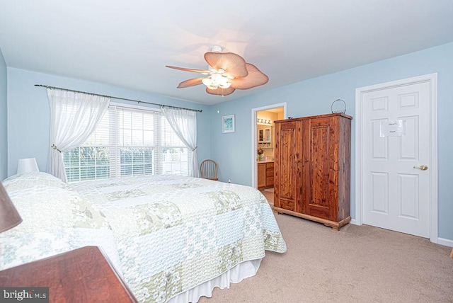 bedroom featuring connected bathroom, light colored carpet, and ceiling fan