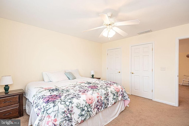 carpeted bedroom with ceiling fan and multiple closets