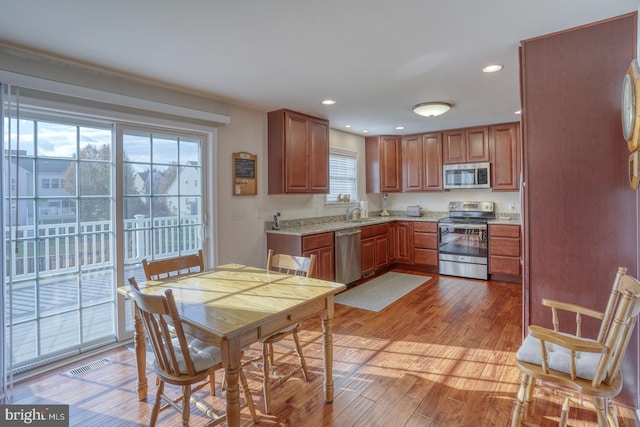 kitchen with stainless steel appliances, light hardwood / wood-style flooring, plenty of natural light, and sink