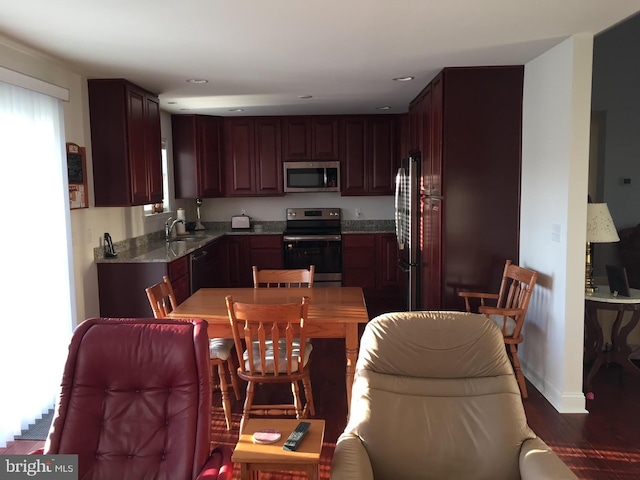 kitchen featuring light stone countertops, dark hardwood / wood-style flooring, stainless steel appliances, and sink