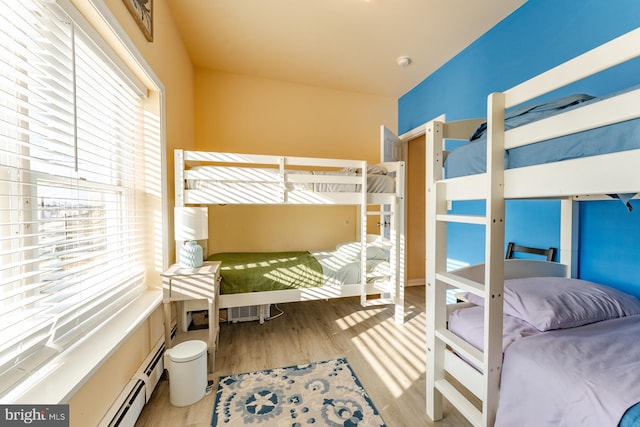 bedroom with a baseboard heating unit and light hardwood / wood-style flooring