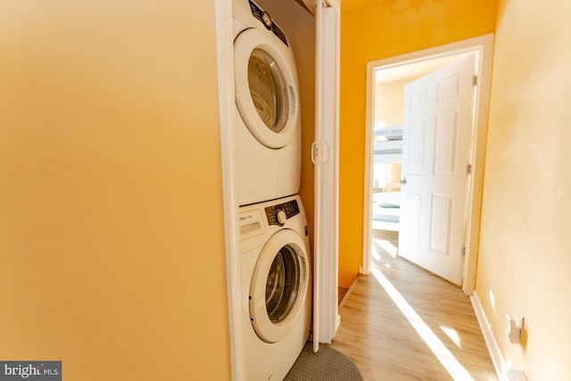 laundry room featuring light wood-type flooring and stacked washer and clothes dryer